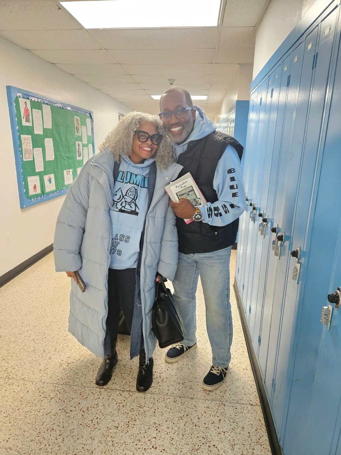 Kelly Walker Edwards and a fellow reader in matching Blue Bishops hoodies, in a locker-lined school hallway